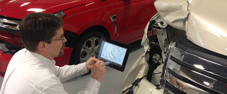 Picture of man inspecting car with tablet